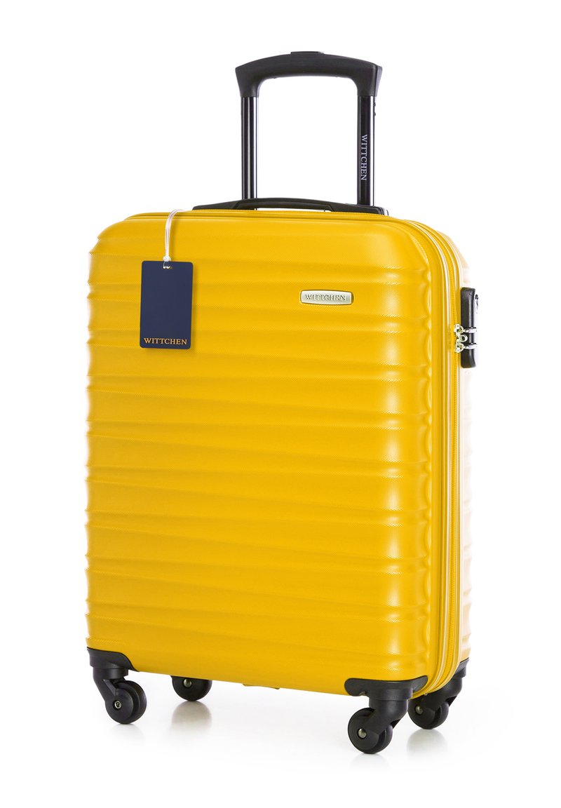 Žlutý kufr s tvrdou skořepinou, vertikálně žebrovaným povrchem, skládacím černým madlem, čtyřmi kolečky a připevněnou modrou značkovou visačkou.