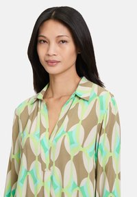 Camicia con colletto a motivo geometrico in verde menta, beige e crema. Tessuto leggero con una consistenza liscia e una vestibilità ampia.