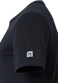 Camiseta negra de manga corta con cuello redondo y una etiqueta gris en la manga izquierda que lleva el texto "FORSBERG". Tejido de algodón suave y liso.