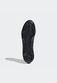 Suola di scarpa sportiva nera caratterizzata da una superficie testurizzata, punte modellate per la trazione e bordi lisci con un design aerodinamico.