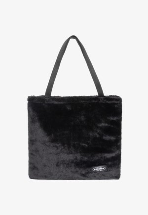 Svart fuskpäls tote-väska med grå handtag, rektangulär form, mjukt material och en liten svart etikett på framsidan.