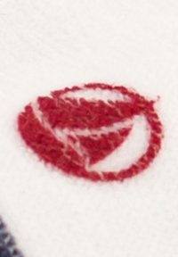 Rød brodert logo på en hvit stoffbakgrunn, med et sirkulært design som har en segmentert bladdesign i sentrum.