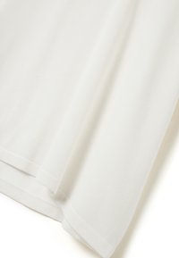 Drappe di tessuto bianco con una texture liscia, caratterizzate da un bordo pulito e da una leggera rigatura, che creano un aspetto morbido e fluido.