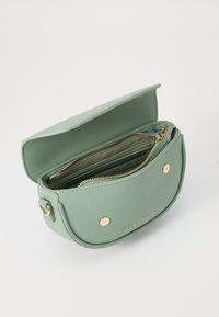 Borsa a tracolla verde in pelle con hardware dorato, forma ovale, chiusura a patta superiore, tasca interna con zip e dettaglio del logo sulla parte anteriore.