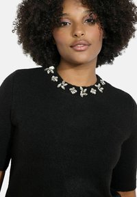 Čierny krátky rukáv sveter s okrúhlym výstrihom zdobeným květinovými kryštálovými detailmi, vyrobený z jemného, textúrovaného materiálu.