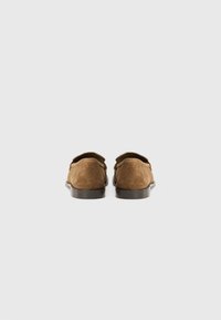 Brown suede loafers with rounded shape, slight heel, and stitched detailing at the edges. Smooth leather sole provides a classic finish.