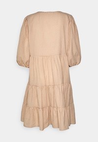 Vestido com padrão de quadrados em pêssego suave e tecido creme. Apresenta mangas bufantes, uma barra em camadas e um decote redondo.