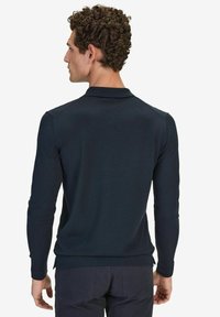 Mörkblå långärmad polo av texturerad stickad sånt, med en krage och sidoförn ämnen för en figursydd look.