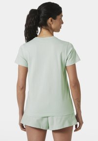 Camisa de manga corta verde menta, material de algodón, escote redondo, corte relajado, combinada con pantalones cortos a juego. Diseño sencillo, sin patrones ni acentos.