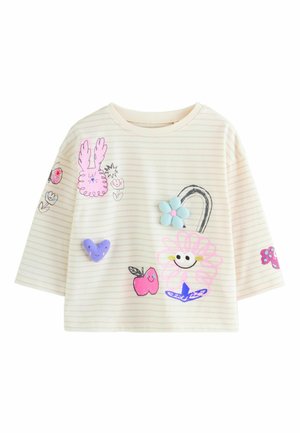 Striped short-sleeve t-shirt in cream featuring colorful appliqué designs including a flower, fruit, and a bunny. Soft fabric texture.