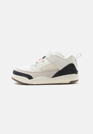 Hvid og sort sneaker med beige detaljer, velcrorem, mesh sidepanel og gummisål set fra ydersiden.