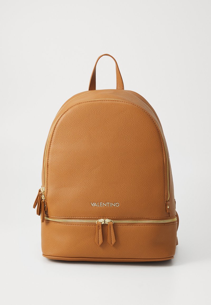 Zaino in pelle tan con finitura texture, parte superiore curva, tasca anteriore con zip, accessori in tonalità oro e nome del marchio "VALENTINO" in argento.