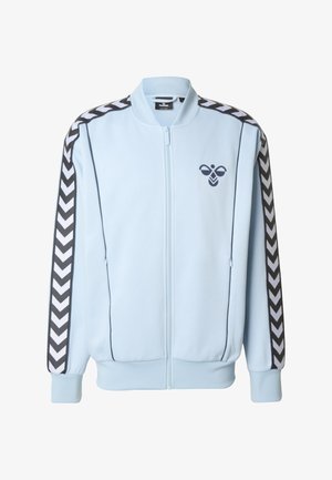 Lichtblauw jack met ritssluiting en een geribbelde kraag, met zwart-witte chevron-strepen op de mouwen en een logo op de borst.