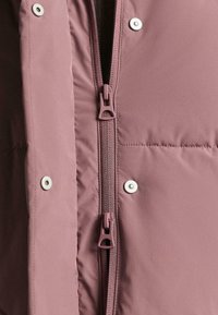 Kurtka puchowa w jasnym kolorze mauve, z centralnym zamkiem błyskawicznym i srebrnymi zatrzaskami. Teksturowana tkanina z przeszywanymi panelami dla izolacji.