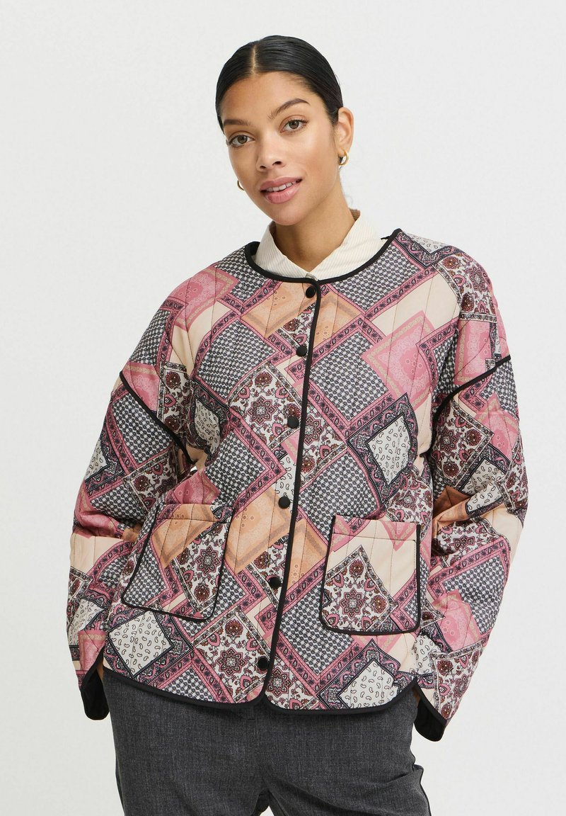 Veste matelassée présentant un design patchwork multicolore en rose, crème et noir. Comprend un col, des boutons et deux poches avant.