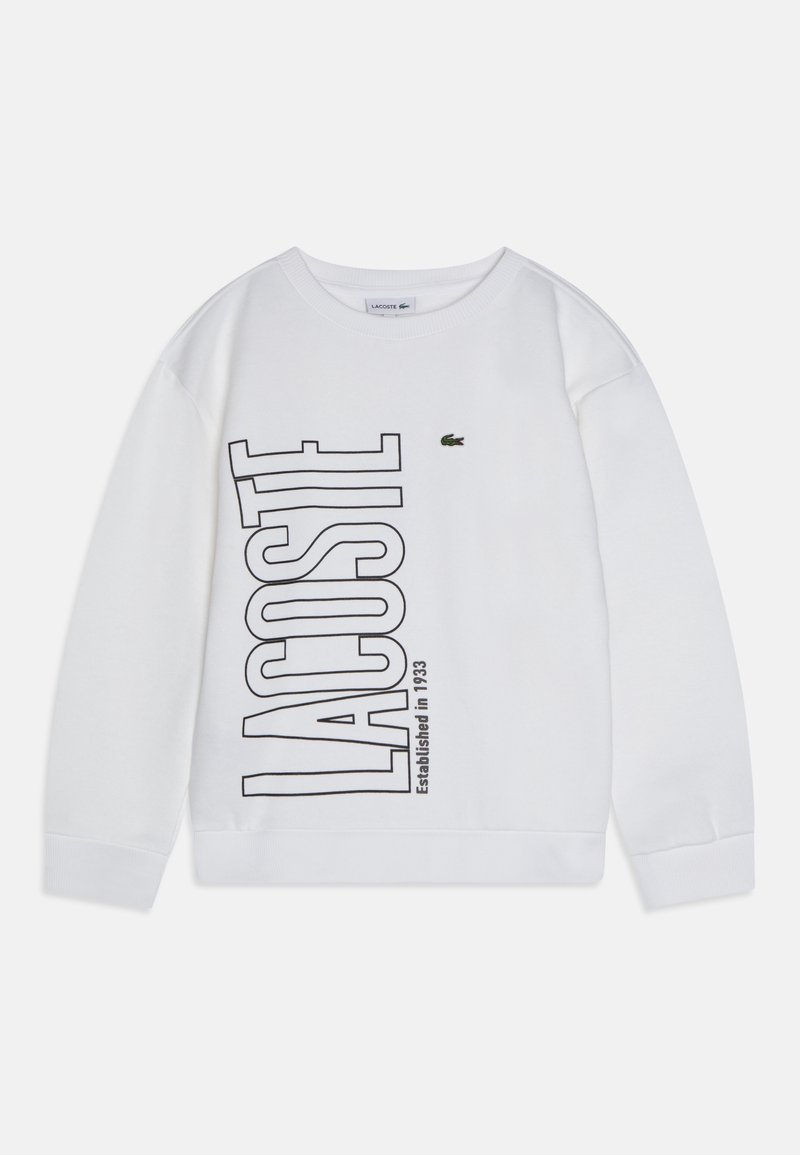 Sweatshirt blanc en coton, avec un grand texte noir "LACOSTE" et "Established in 1933". Logo crocodile vert sur le côté supérieur gauche.
