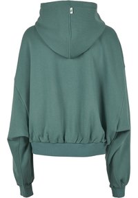 Kapuzenpullover v mudro zeleni barvi z udobnim krojem, ribanim robom in spuščeni rameni. Ima gladko tkanino in majhno oznako blagovne znamke.