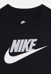 Mustmust T-särk, millel on suur hall Nike logo ja valge swooshi disain. Ümar kaelus ja silmapaistvad õmbluse detailid.