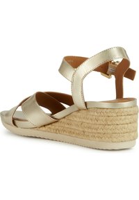 Sandalo wedge in metallo dorato con base in stile espadrilles intrecciata, cinturino alla caviglia e fasce incrociate nella parte anteriore. Finitura morbida e testurizzata con suola in gomma.