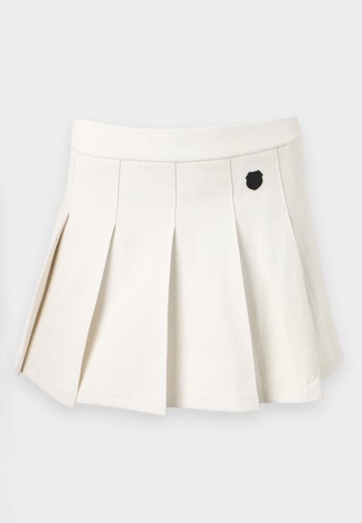 Pleated white skirt made of cotton-blend fabric, featuring a black emblem on the front and an elastic waistband for comfortable fit.