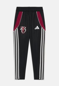 Pantalones deportivos negros con paneles laterales rojos, tres franjas blancas en cada pierna, un logo bordado y aperturas con cremallera en los tobillos.
