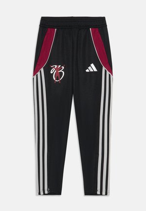 Zwarte sportbroek met rode zijpanelen, drie witte strepen langs elk been, een geborduurd logo en ritsen bij de enkels.