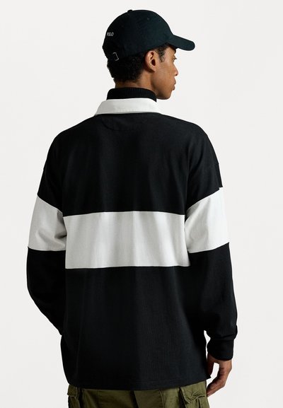 Langarm polo shirt in zwart-wit gestreept, met een kraag en geribbelde manchetten. Gecombineerd met olijfgroene cargobroek.