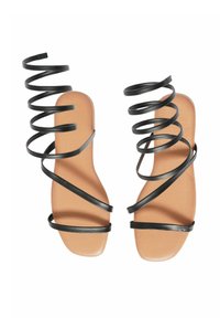 I sandali neri con cinturino a spirale presentano una suola piatta color cammello, con molteplici sottili cinturini incrociati per supporto e un design elegante.