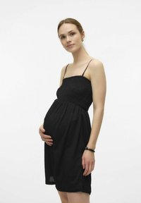 Robe de maternité noire sans manches avec un buste smocké et une jupe fluide, dotée de fines bretelles. Texture douce, conception à mi-genoux.
