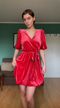 Röd sammet omlottklänning med korta puffärmar, knyt i midjan och en utsvängd kjol. Mjuk textur med glansig yta.