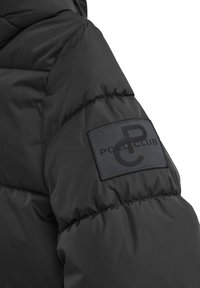 Czarna pikowana kurtka z podszewką. Posiada prostokątną czarną łatę z wytłoczonym logo "POLO CLUB" na rękawie.