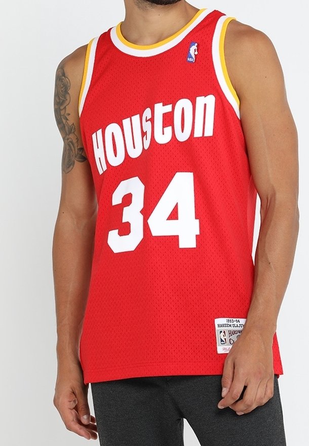Mann in einem ärmellosen roten Basketball-Trikot aus Houston mit der Nummer 34, Tätowierung am linken Arm und schwarzen Hosen.