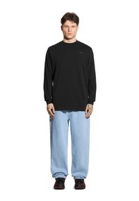 Czarna, długosleeve'owa koszula z okrągłym dekoltem, połączona z jasnoniebieskimi, oversize'owymi dżinsami oraz czarnymi sneakersami z czerwonymi akcentami. Prosty i casualowy styl.