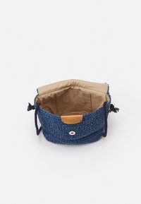 Borsa intrecciata blu con fodera in tessuto beige, caratterizzata da un'etichetta in pelle liscia e un dettaglio decorativo a bottone. Chiusura con cordoncino regolabile.