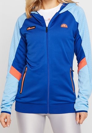 Giacca sportiva blu con zip, dettagli azzurri, tiranti arancioni, due tasche frontali e cappuccio, realizzata in materiale sintetico liscio.