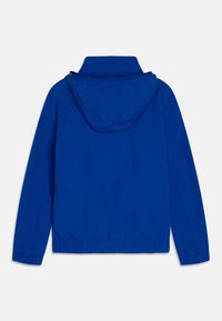 Giacca blu con cappuccio, dotata di polsini e orlo elasticizzati, caratterizzata da una texture liscia e un design minimalista. La vista posteriore evidenzia il cappuccio e la finitura senza cuciture.