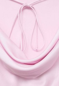 Top in satin rosa con scollo a cappuccio e dettaglio con lacci sulla parte posteriore. Il tessuto è morbido e leggermente lucido, creando pieghe morbide.