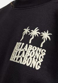 Felpa nera con logo ricamato bianco "BILLABONG" in un design impilato, arricchita da tre grafiche di palme. Texture morbida.