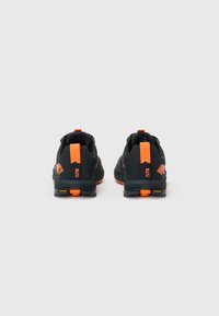 Des chaussures de sport noires avec des accents oranges. La vue de dos montre un tissu texturé, un col rembourré et une languette. La semelle présente des couleurs contrastantes.