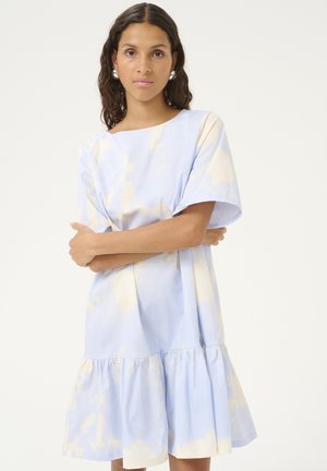 Vaaleansininen mekko, jolla on leveä helma, pehmeitä beigejä roiskeita, lyhyet hihat ja venepääntie. Valmistettu sileästä puuvillakankaasta.