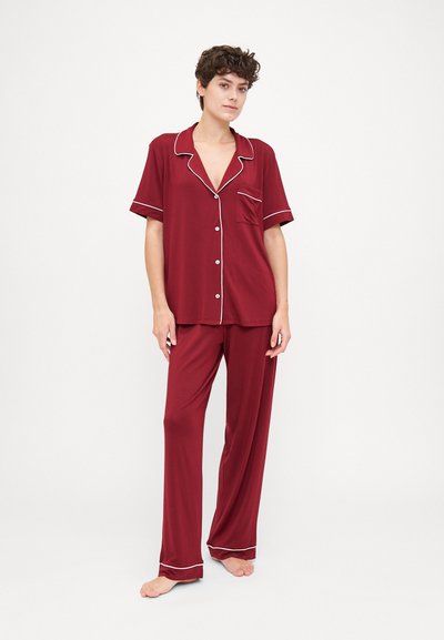 Maroon two-piece pajama set made of soft fabric, featuring a short-sleeve button-up top with white piping and matching pants.