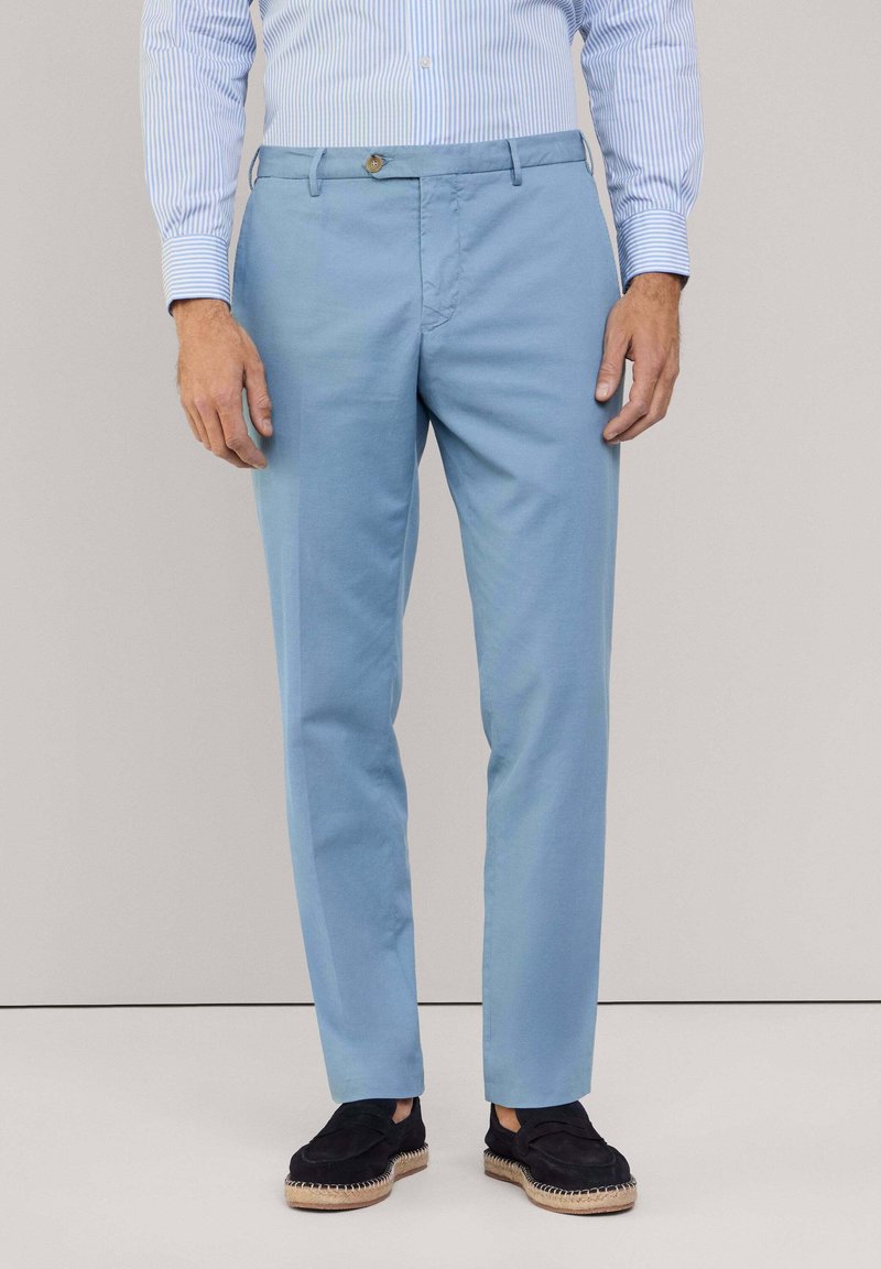 Lichtblauwe broek van zachte stof, slim fit ontwerp met een flat front, voorzien van een knoopsluiting en zijzakken. Gecombineerd met zwarte schoenen.