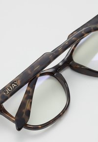 Skilpadde-sunglasses med gradientlinser, som har brede rammer og en gull "QUAY"-logo på bøyle. Glatt plasttekstur.