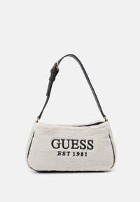 Witte pluche handtas met een zwarte leren band en goudkleurige hardware. "GUESS EST 1981" is in het zwart op de voorkant geborduurd. Rechthoekige vorm.