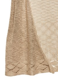 Strickschal in sandbeige, mit offener Webstruktur und einem gemusterten Saum mit wellenförmigen Akzenten. Leicht und atmungsaktiv.