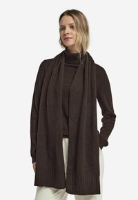 Mørkebrun tørklæde lavet af blødt, tekstureret stof. Har en ribbet kant og hænger elegant, hvilket komplementerer en højhalset top.