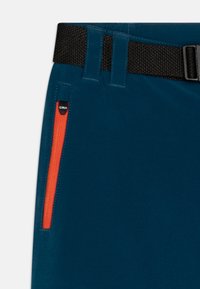 Tirkizne hlače s teksturiranim crnim pojasom, koje imaju džep s patentnim zatvaračem s narančastim detaljem i logom. Glatka tkanina s izdržljivim šavovima.