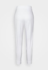 Vita bomullsjoggers med en avsmalnande passform, elastisk midja och ribbade muddar. Slät textur, inga mönster eller metallföremål synliga.