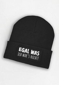 Black knit beanie with a textured finish. Features a rectangular patch with white text: "EGAL WAS ICH WAR'S NICHT!"
