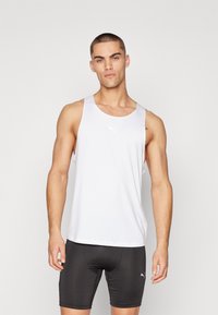 Hvid træningstop med rund halsudskæring og PUMA-logo. Båret med tætsiddende sorte shorts, der fremhæver en minimalistisk stil og glat tekstur.